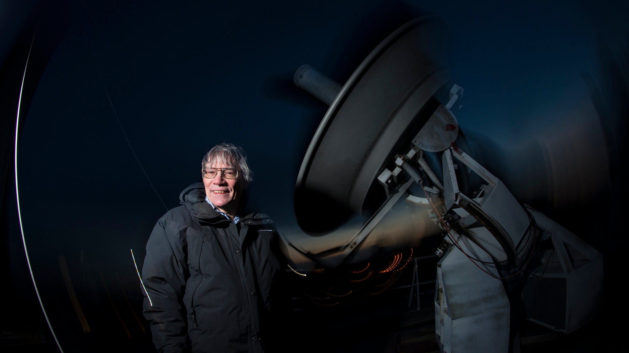 Scientist Alan Guth standing in front of a telescope